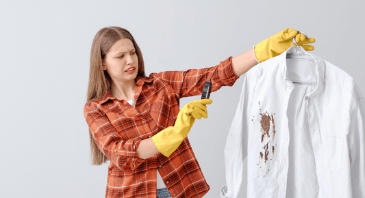 Frau mit gelben Putzhandschuhen hält Hemd zum Flecken entfernen