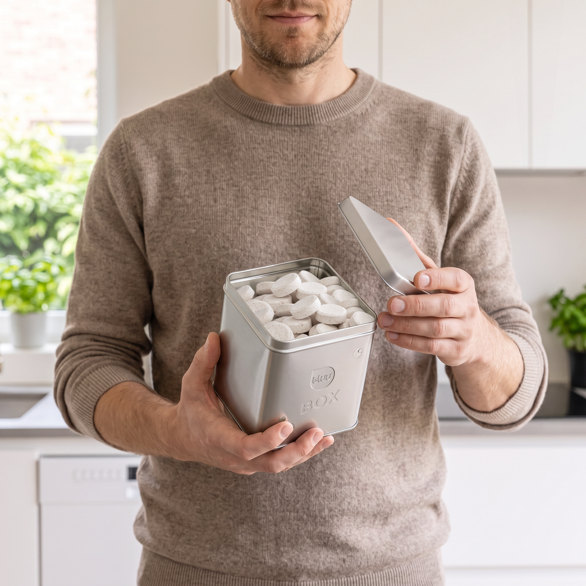 Mann hält offene bluu box gefüllt mit Spülmaschinentabs Bluufos
