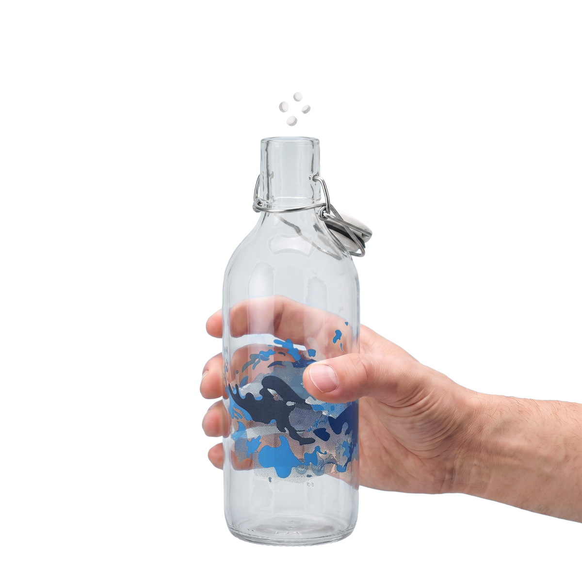 Hand hält eine Glasflasche mit Wasser und sprudelndem Cleanions Tab