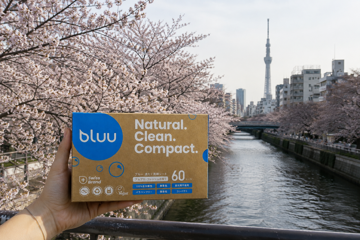 Hand hält eine bluu Waschstreifen-Packung vor Kirschblüten und dem Tokyo Skytree